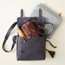 Grey handmade canvas satchel styled with laptop sleeve, water bottle, charging cable and organiser pouch.