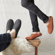 Rust brown wool MITA mule slippers worn at home beside charcoal grey felted wool slippers.