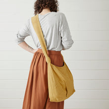 Mustard yellow handwoven cotton crossbody bag worn across the body with long comfortable strap.